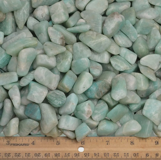 A person holding a tumbled amazonite stone in their hand