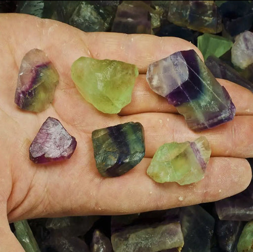 A large, raw rainbow fluorite crystal with a rough texture